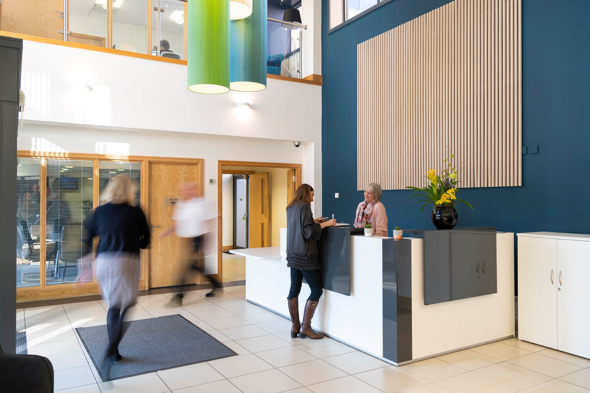 The atrium reception at City Gateway with colourful pendant lighting and people walking through